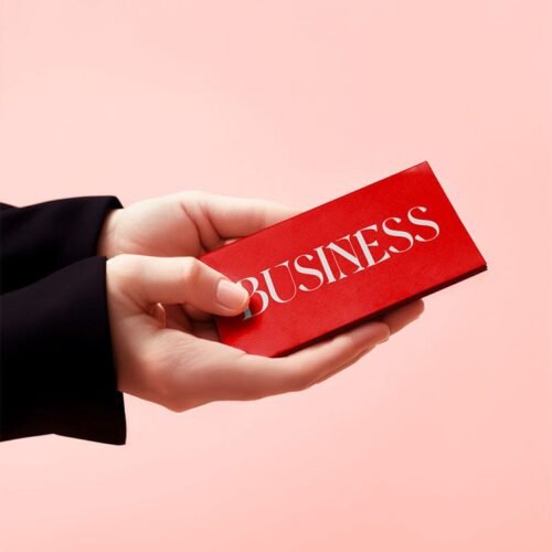 Hands holding a business card, pink background