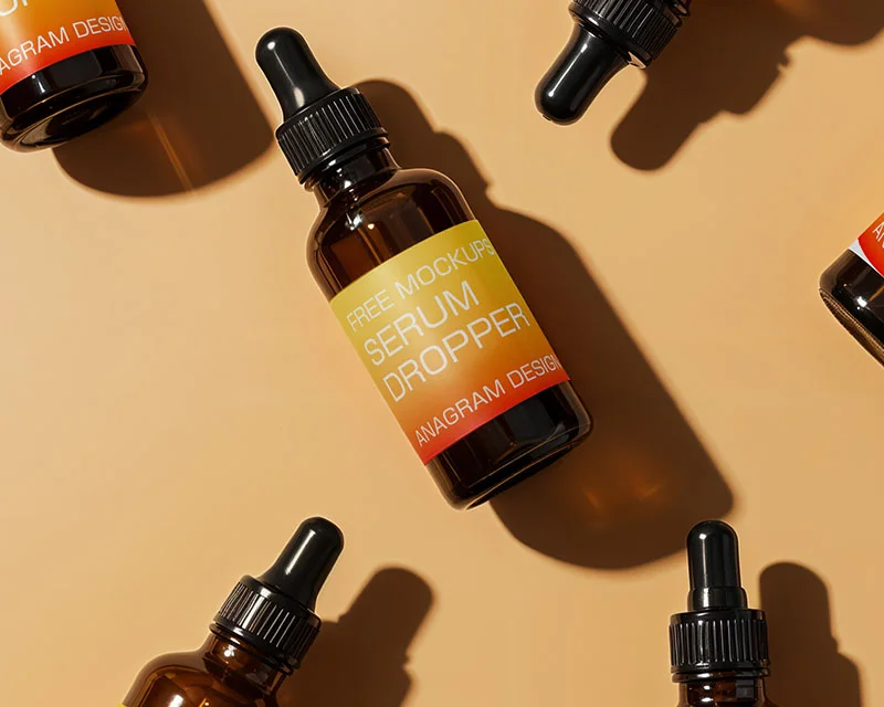 Amber glass serum dropper bottles with black caps arranged on a light beige background.