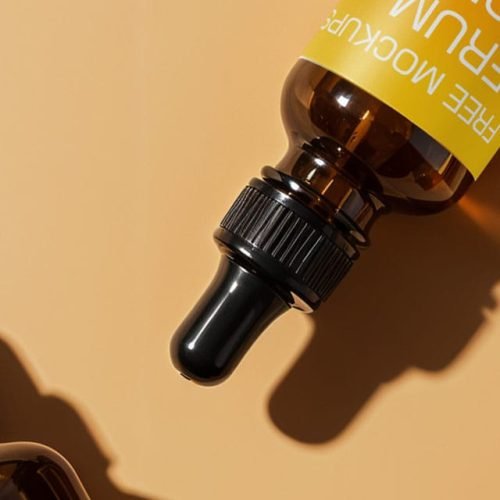 Amber glass serum dropper bottles with black caps arranged on a light beige background.