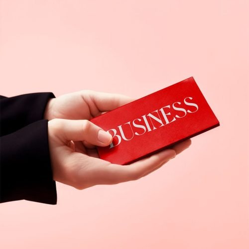 Hands holding a business card, pink background